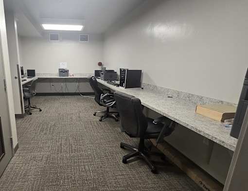 A room with a row of desks and chairs.