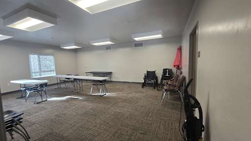 A room with tables and chairs and a wheelchair.