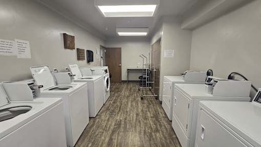 A laundromat with washers and dryers lined up.