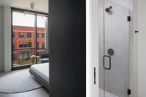 A modern bedroom with a large bed and a glass door leading to a balcony at Miles at Ybor Apartments, Tampa, Florida