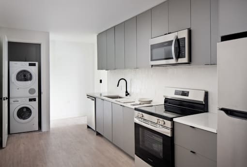 A modern kitchen with a washing machine and a microwave at Miles at Ybor Apartments, Tampa 33605