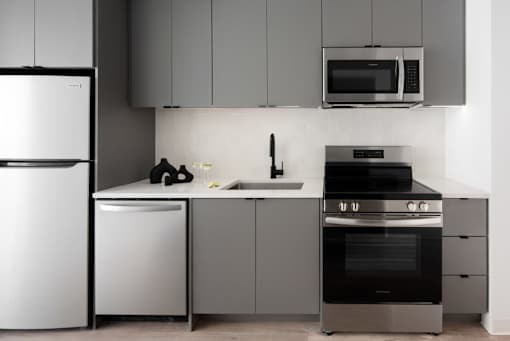 A modern kitchen with a white refrigerator, microwave, and stainless steel appliances at Miles at Ybor Apartments, Tampa, FL, 33605