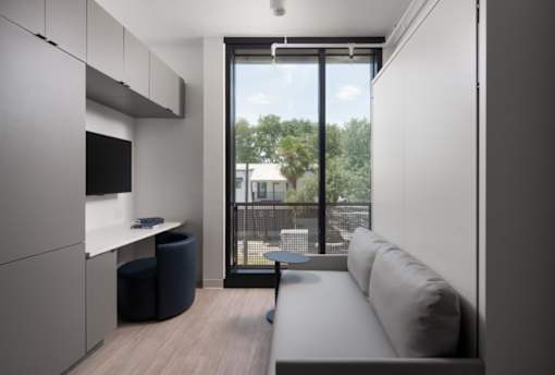 A modern living room with a couch, a chair, and a television at Miles at Ybor Apartments, Tampa