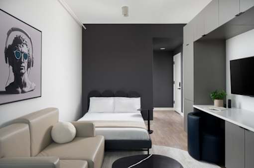 A modern bedroom with a large bed and a couch at Miles at Ybor Apartments, Florida