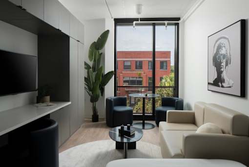 A living room with a large window overlooking a red building at Miles at Ybor Apartments, Florida, 33605