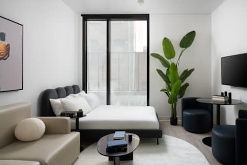 A living room with a large window, a sofa, a coffee table, and a potted plant at Miles at Ybor Apartments, Florida