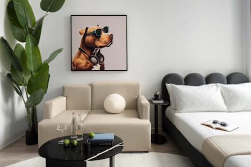 A living room with a beige couch, a black coffee table, and a framed picture of a dog wearing sunglasses at Miles at Ybor Apartments, Tampa