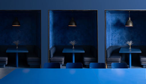 A blue table is in the middle of a room with three chairs and three lamps at Miles at Ybor Apartments, Tampa, FL, 33605