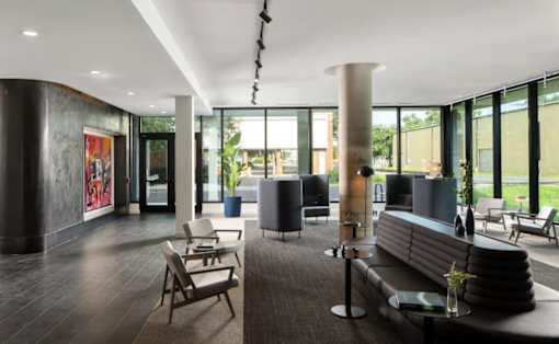 A modern waiting room with a long bench and a table with a vase of flowers on it at Miles at Ybor Apartments, Tampa, FL