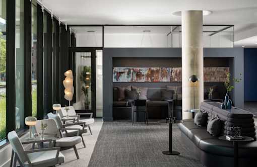 A modern living room with a black couch and grey chairs at Miles at Ybor Apartments, Tampa, FL