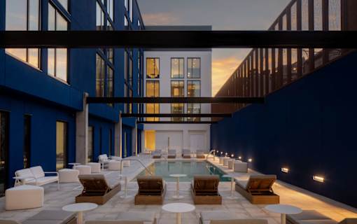 A modern outdoor pool area with lounge chairs and tables at Miles at Ybor Apartments, Tampa, FL