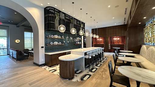 A modern restaurant with a bar area and wooden floors.