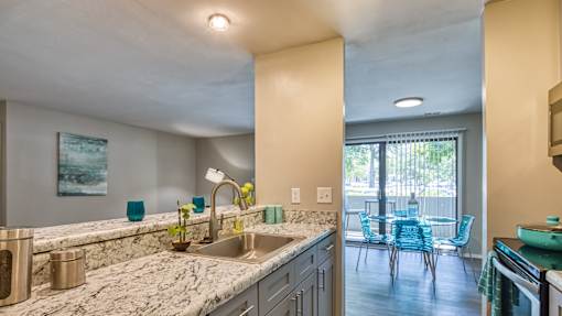 A kitchen with a marble countertop and blue chairs.