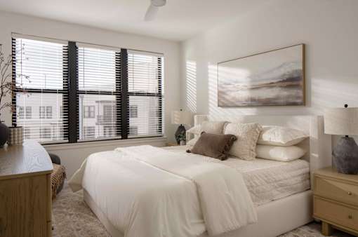 A bedroom with a large bed and a painting on the wall.