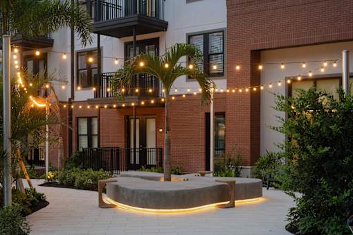 A modern courtyard with a circular stone platform and a palm tree.