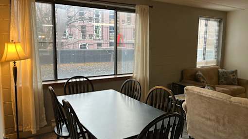 A dining room with a table, chairs, and a lamp.
