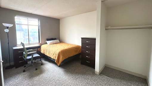 A bedroom with a bed, desk, and chair.