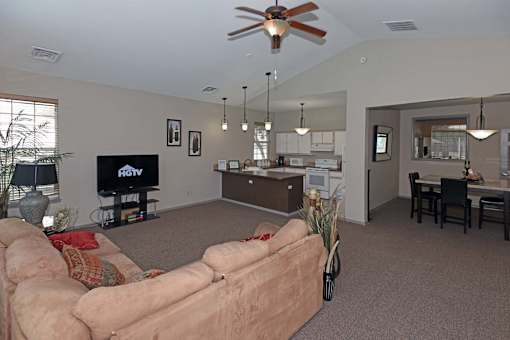 A living room with a couch, television, and a ceiling fan.