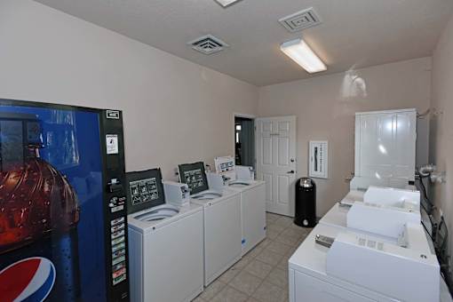 A room with a Pepsi machine on the left and a washing machine on the right.