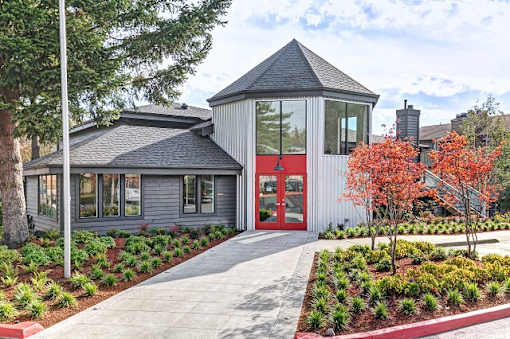 Exterior of Hangar 128 Apartment Homes with turret style architecture and a red door at Hangar 128 Apartments Homes in Everett, WA