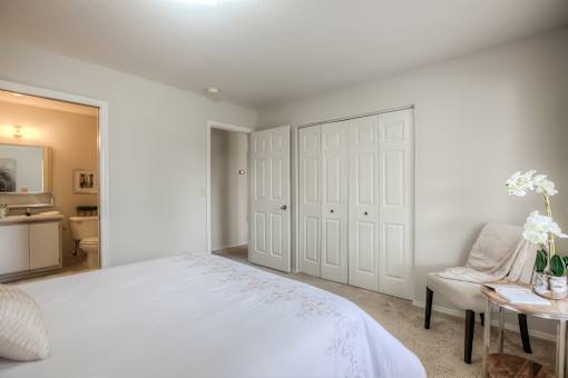 A white bedroom with a large bed and a vanity with a mirror.