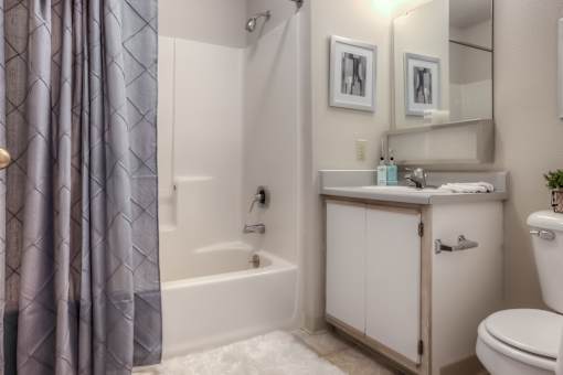 A white bathroom with a grey shower curtain.