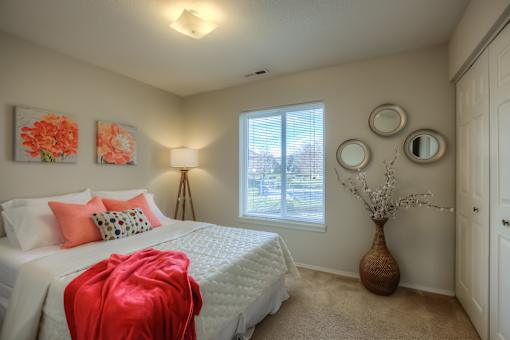 A bedroom with a white bed and a red blanket.
