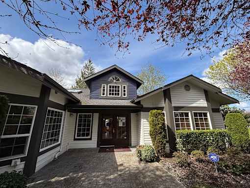 A house with a blue roof and a brown door is surrounded by green bushes at Waterford Apartments, Everett, Washington