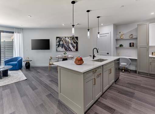 A modern kitchen with a large island and a TV mounted on the wall.