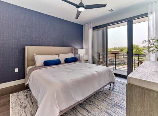 A bedroom with a large bed and a balcony.