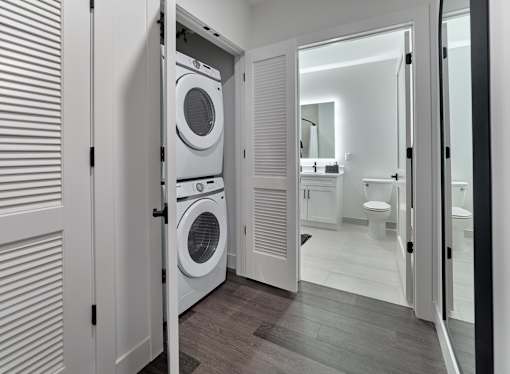 A white laundry room with a washer and dryer built into the cabinetry.