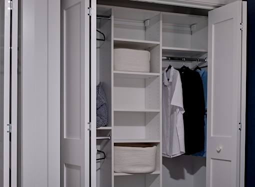 A white closet with clothes hanging and shelves.