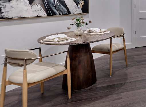 A wooden table with two chairs and a vase with flowers on top.