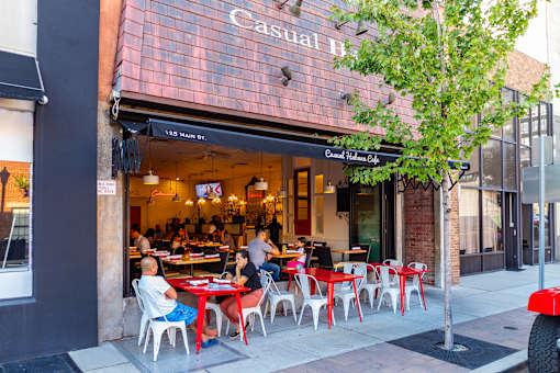 A restaurant named Casual Hut has tables and chairs set up on the sidewalk.