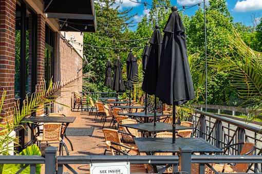 A patio with tables and chairs and umbrellas.