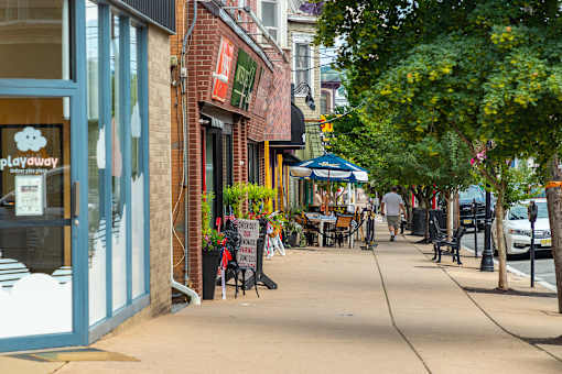 A sidewalk with a blue umbrella and a sign that says