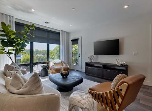 A living room with a large window, a flat screen TV, and a wooden chair.