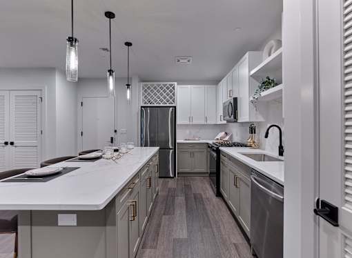 A modern kitchen with a white countertop and dark wood flooring.