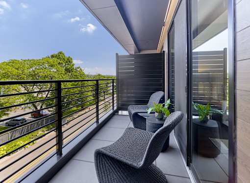 A balcony with a chair and a table with a plant on it.