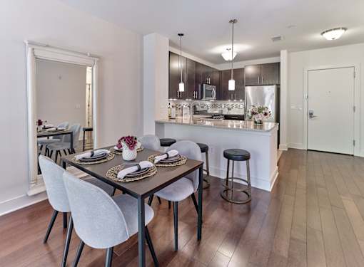 A modern dining room with a wooden table and white chairs.