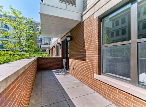 A balcony with a brick wall and a glass door.