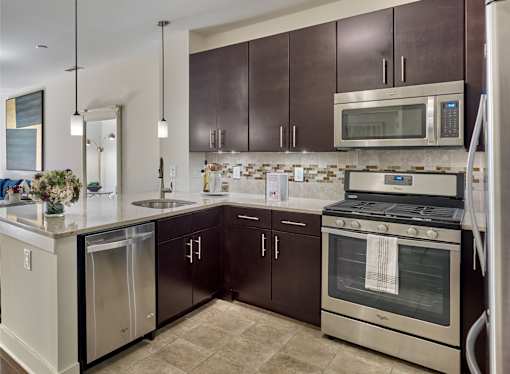 A modern kitchen with espresso cabinets and stainless steel appliances.