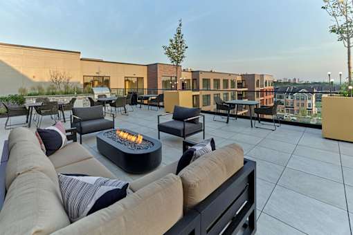 A modern outdoor seating area with a fire pit in the center.