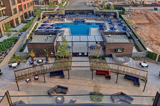 A large outdoor pool surrounded by a fence and seating area.