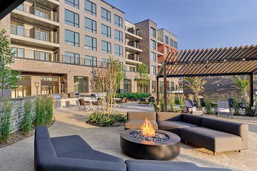 A modern outdoor seating area with a fire pit in the middle.