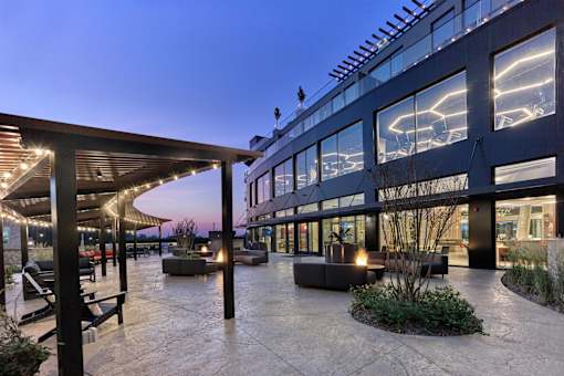 A modern building with a glass facade and a patio area with a fire pit.