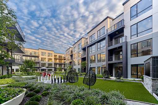 A modern apartment complex with a landscaped garden in front.