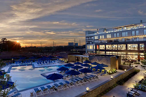 A sunset view of a pool area with lounge chairs and umbrellas.