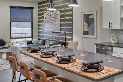 A modern dining room with a long table set for a meal.