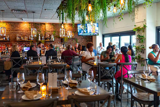 A restaurant with people dining and a bar in the background.